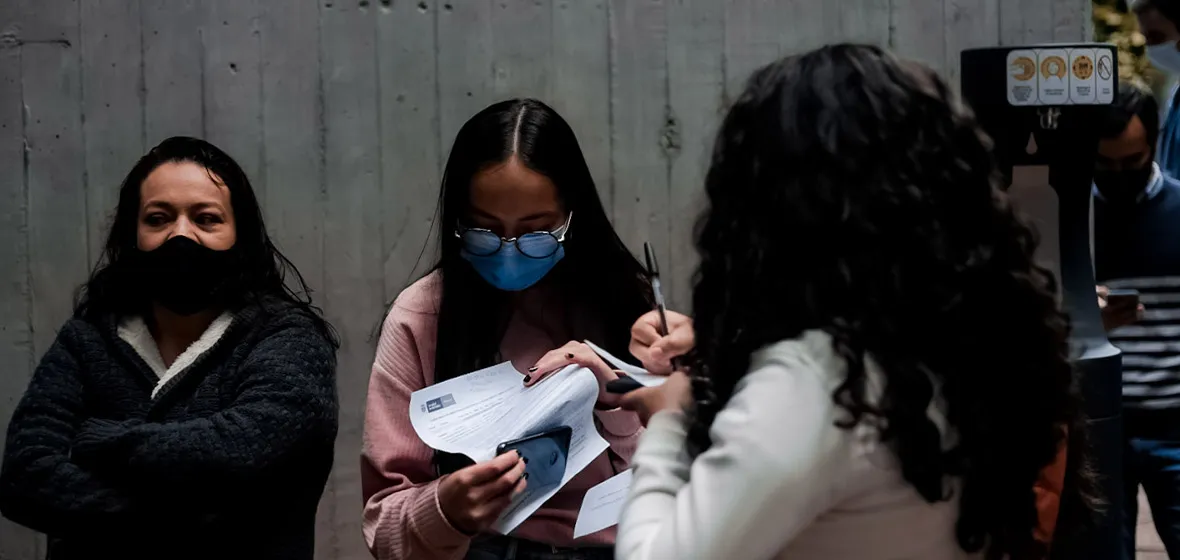 Mujeres diligenciando formatos para vacunación 