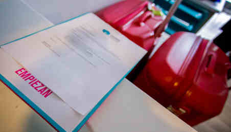 Imagen de un formulario sobre una mesa con el fondo de un equipaje. 