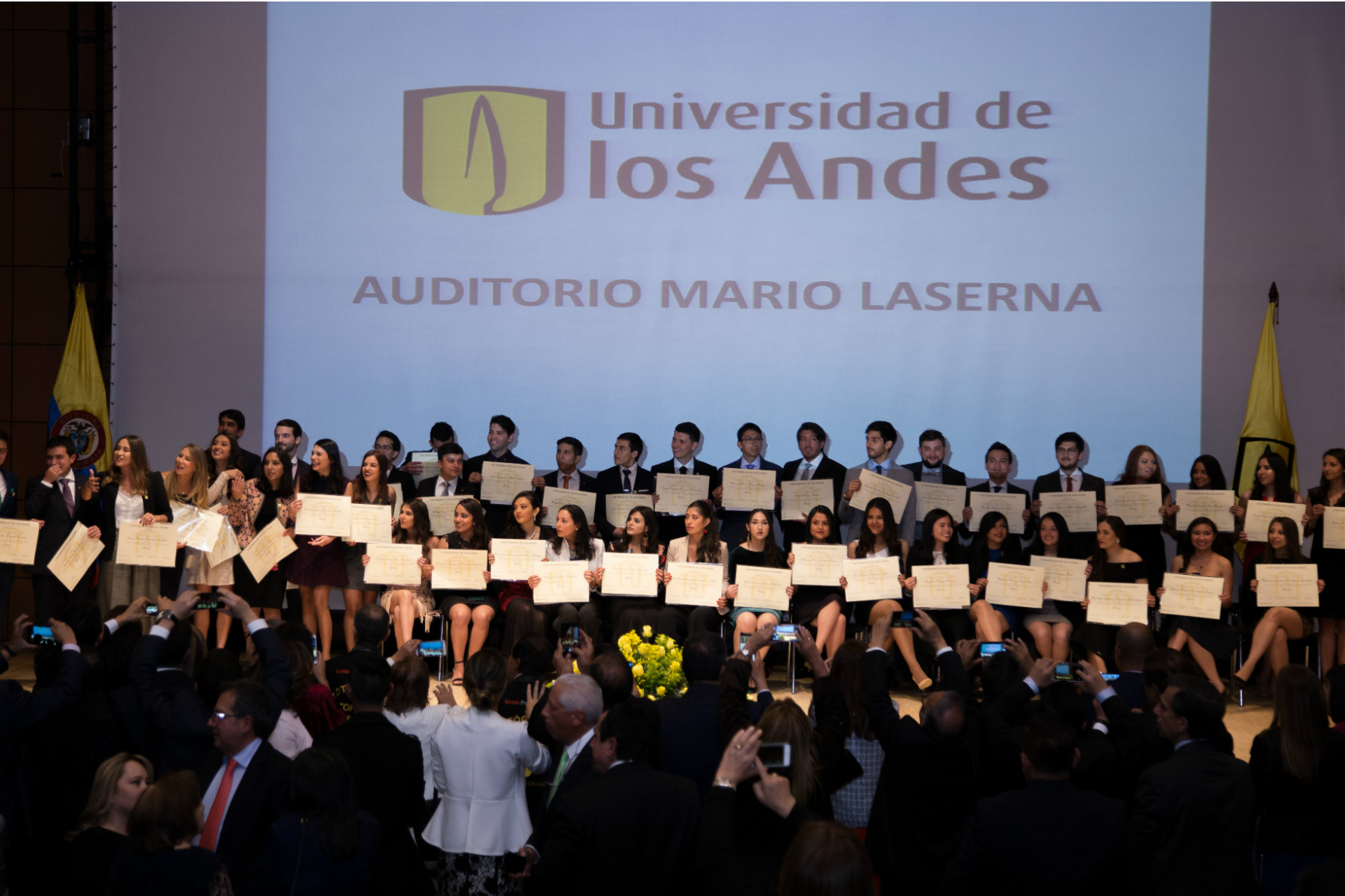 Imagen de todo un grupo de graduandos, sosteniendo su diploma.