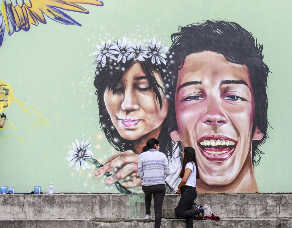 Jóvenes observan mural en homenaje a Margarita Gómez y Mateo Matamala