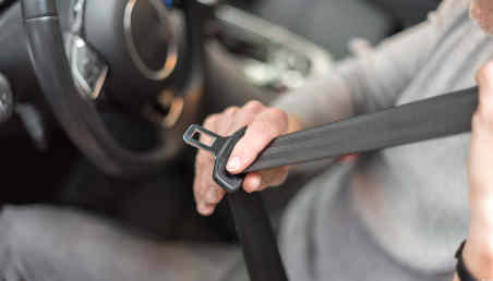 Un hombre a punto de cerrar su cinturón de seguridad en un auto.