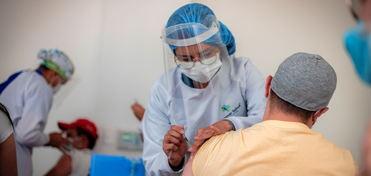 Hombre vacunandose de espaldas con personal de salud