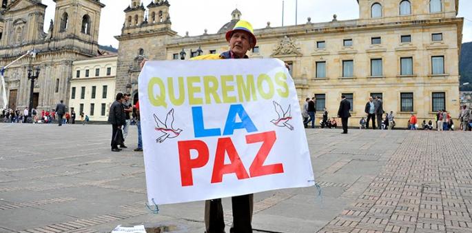 Foto de un hombre con un cartel que dice queremos la paz