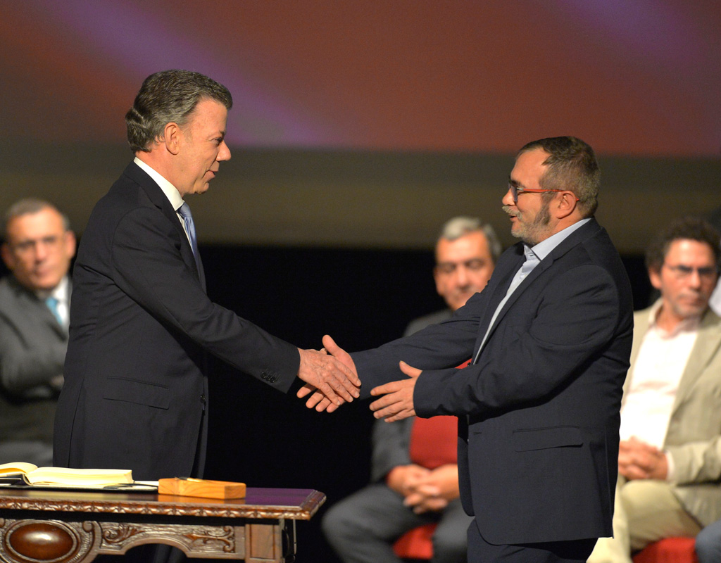 El Presidente de Colombia, Juan Manuel Santos y el jefe de las Farc, Rodrigo Londoño, alias 'Timochenko', se saludan luego de firmar el acuerdo de paz.