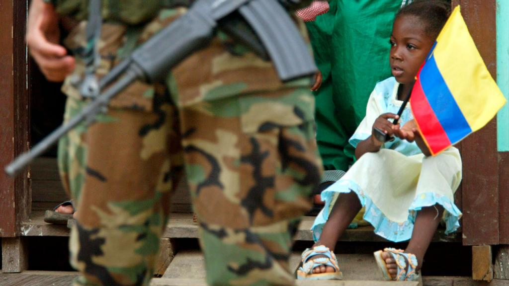 Afrocolombian little girl holding the national flag alongside a soldier