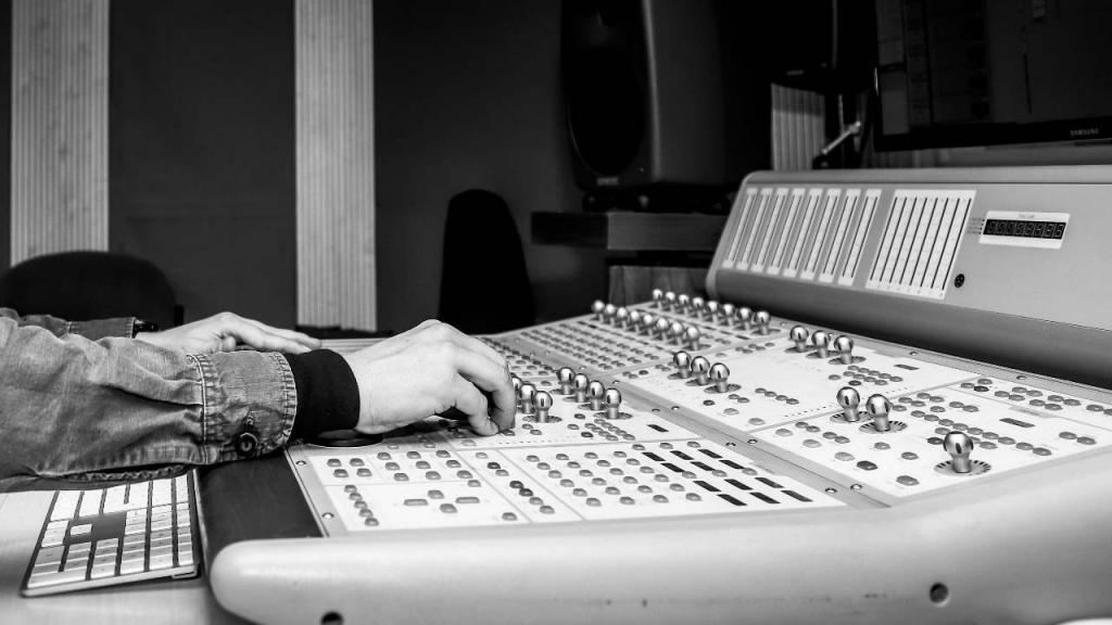 Hands control an audio recording console in the Los Andes studio.