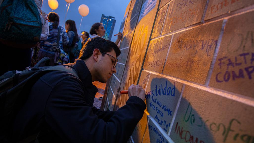 Un estudiante pinta un mensaje en un muro