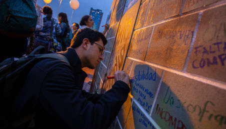 Un estudiante pinta un mensaje en un muro