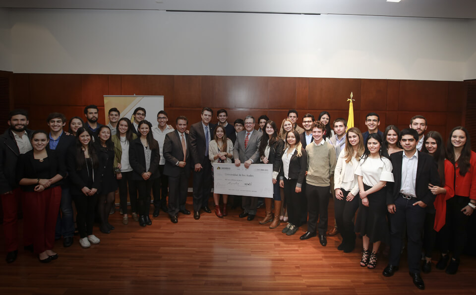 Grupo de egresados y el rector de la Universidad de los Andes posan para al foto sosteniendo un cheque gigante