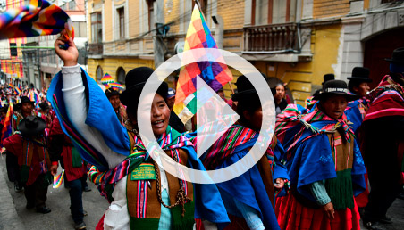 Mujeres indígenas Aymara de Bolivia caminando con banderas.