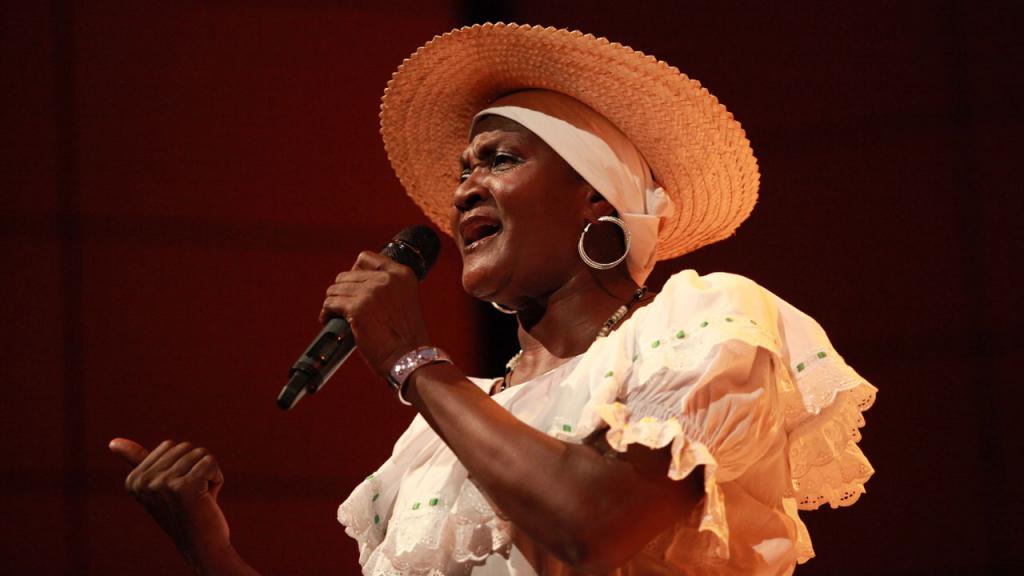Mujer afrodescendiente canta en un auditorio