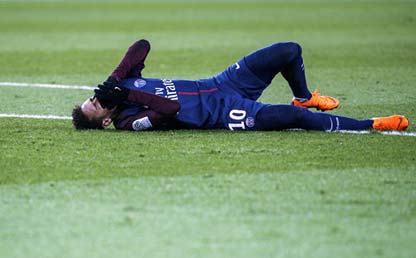 El futbolista Neymar lesionado postrado en el césped se toma la cara con dolor. Foto: AFP