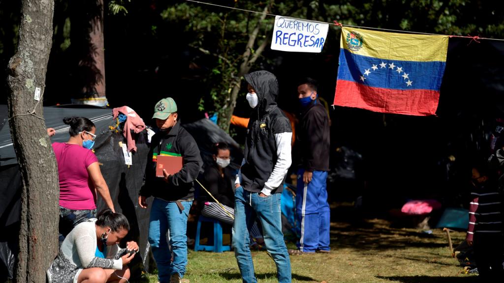 Foto de la bandera de Venezuela con un cartel de queremos regresar