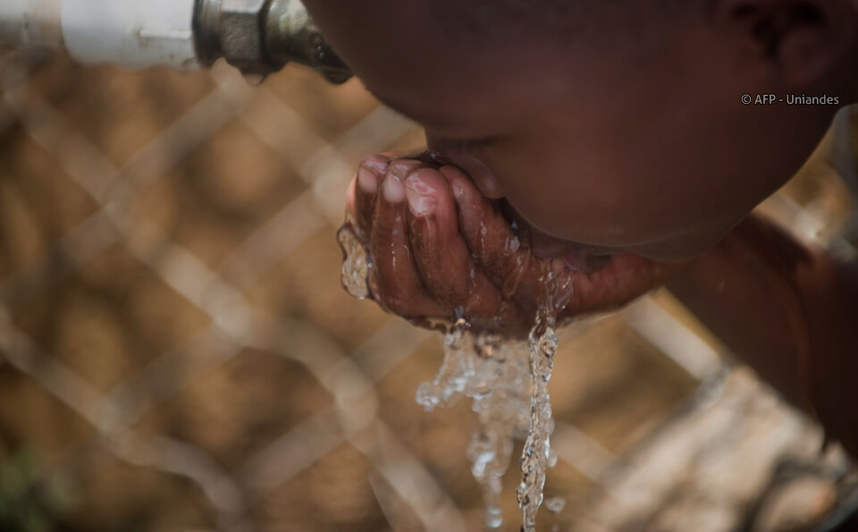 niña afrodescendiente bebiendo agua con mano