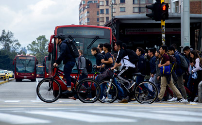 Ciclistas y peatones cruzando una avenida en Bogotá.