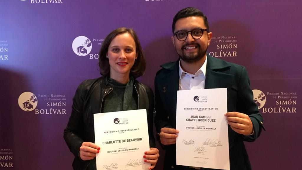Dos personas, ganadoras del Premio Simón Bolívar, posan con un diploma