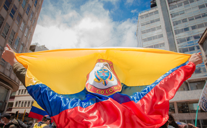 Un manifestante se arropa con la bandera de Colombia.