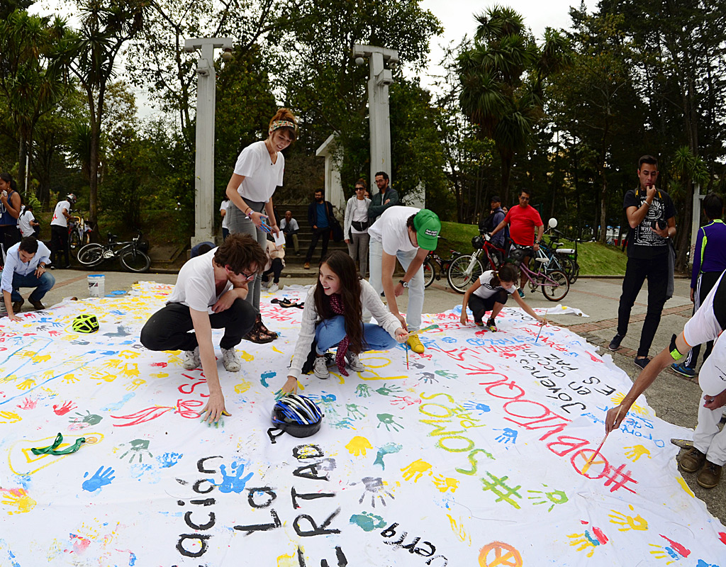 Jóvenes pintando banderas blancas con mensajes de paz.