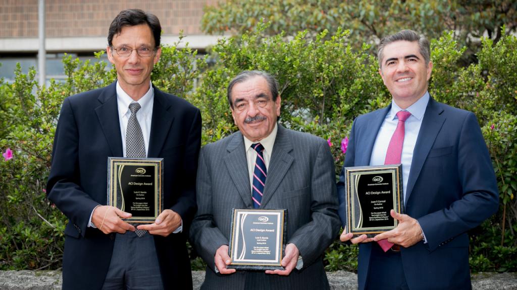 Tres profesores de la Universidad de los Andes exponen placas de reconocimiento. 
