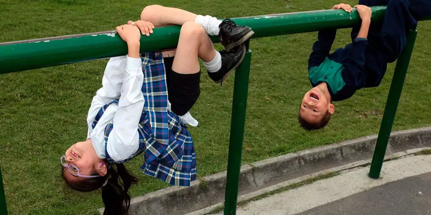 Niña y niño juegan en una baranda