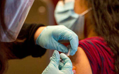 Foto de personal médico aplicando una vacuna a una mujer